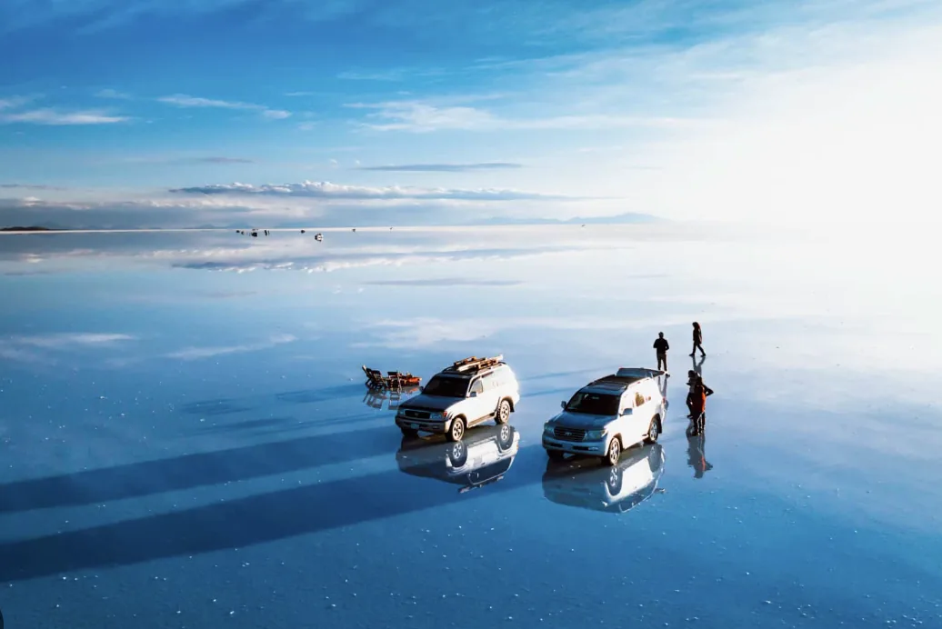 Vehículos 4x4 cruzando el Salar de Uyuni con efecto espejo