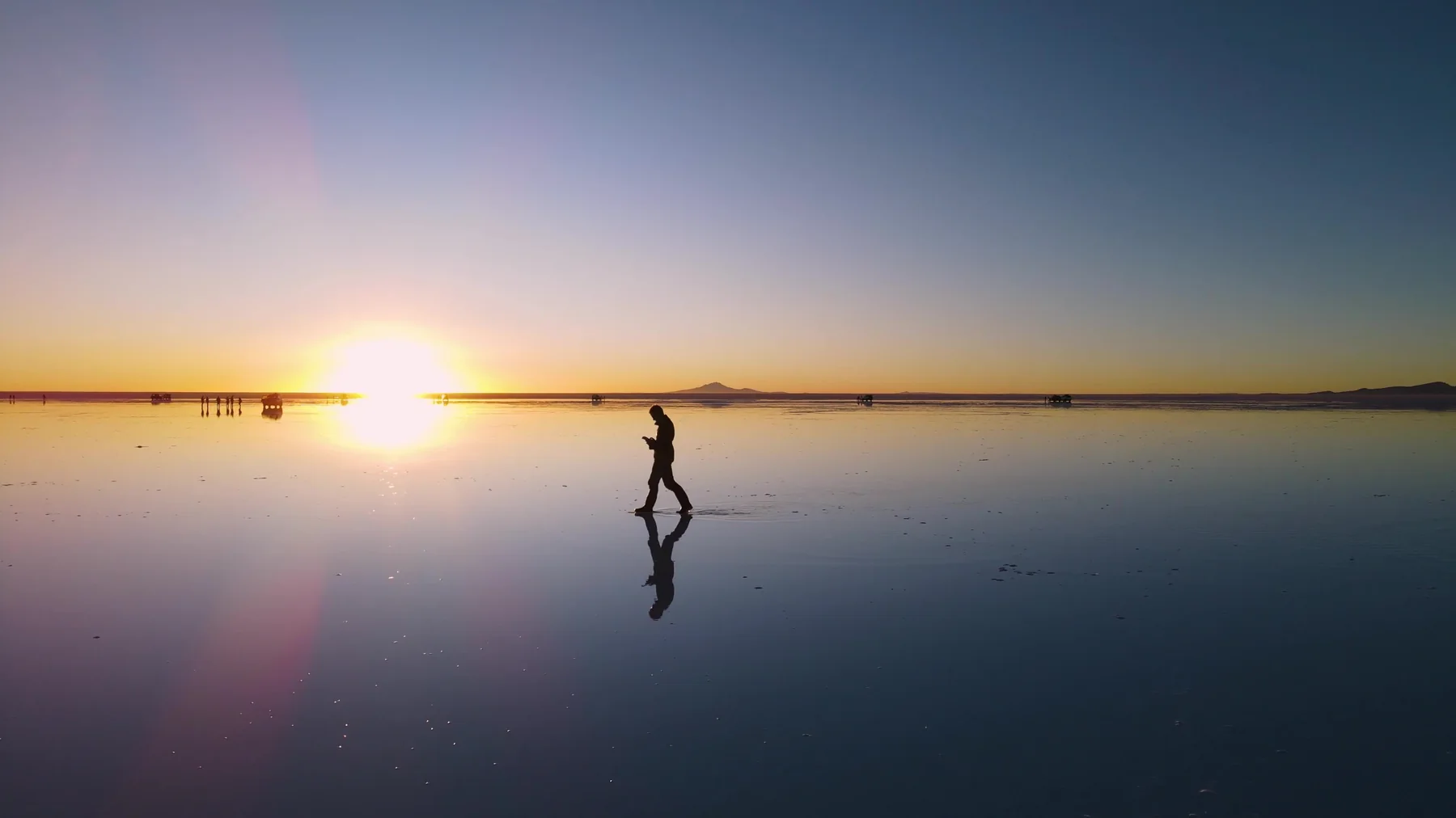 Viajeros fotografiando el atardecer reflejado en el Salar de Uyuni