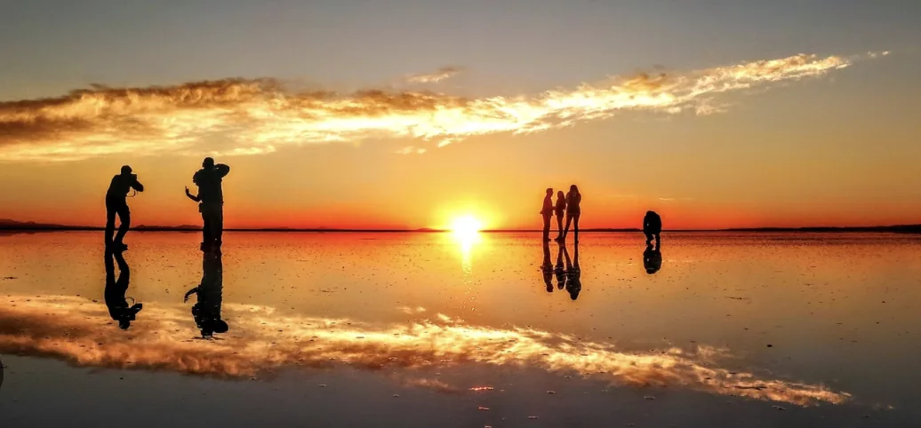 Viajeros fotografiando el atardecer reflejado en el Salar de Uyuni